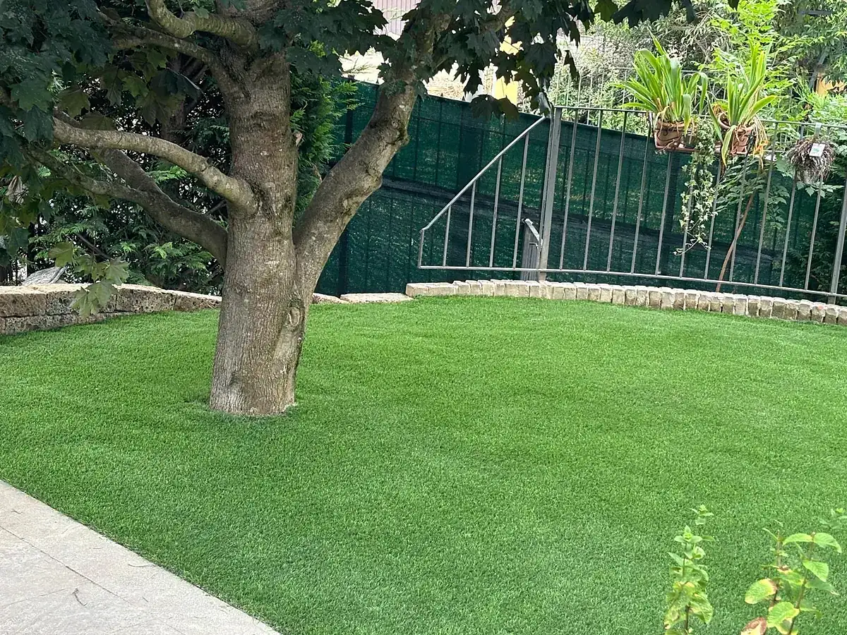 Giardino privato con prato in erba sintetica attorno a un grande albero