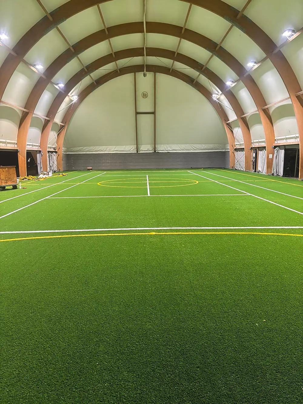 Impianto sportivo indoor con campo in erba sintetica sotto struttura ad arco