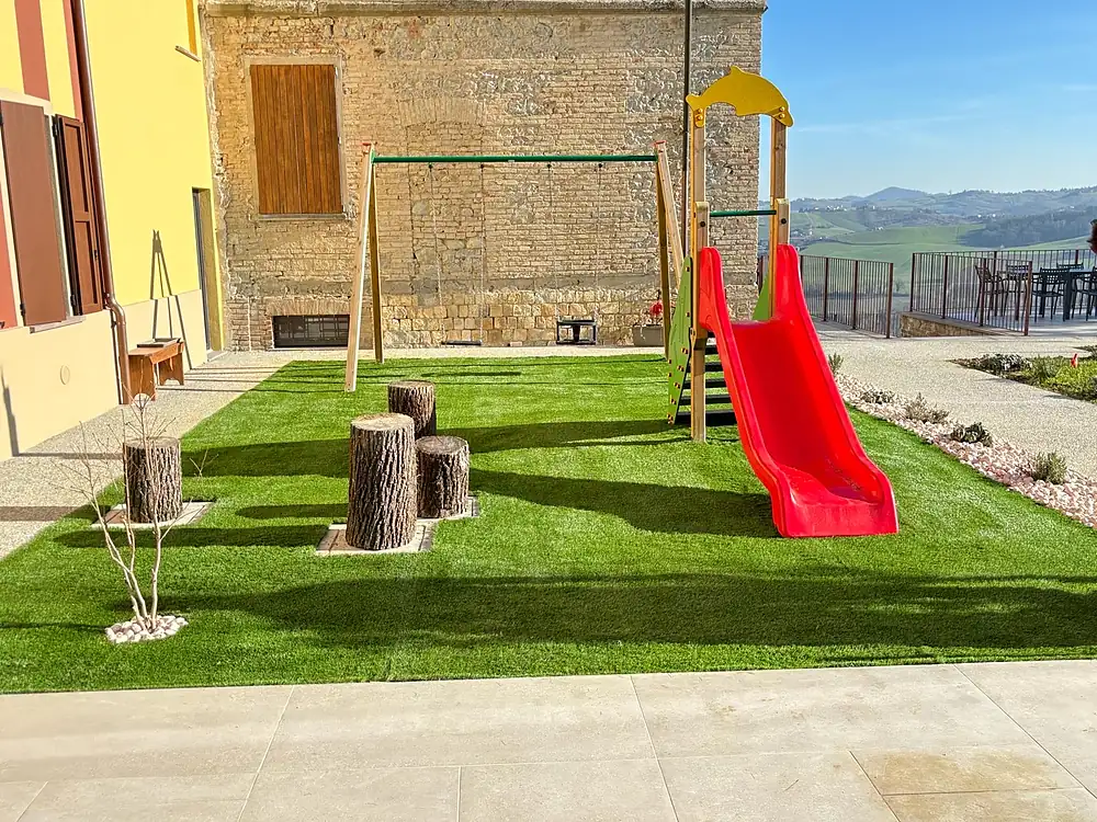 Area giochi per bambini con prato sintetico e scivolo